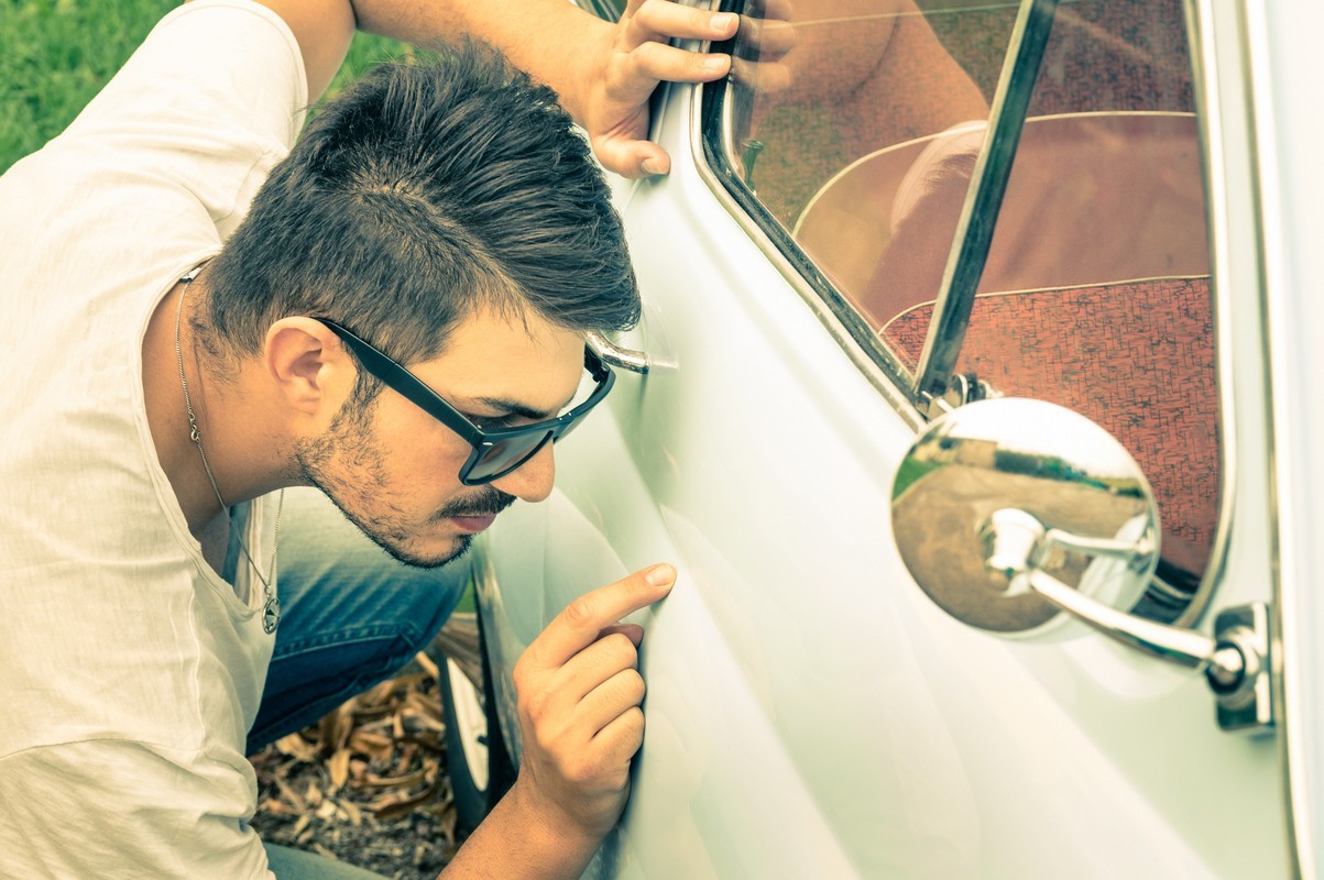 Guy Looking At His Car For Any Marks